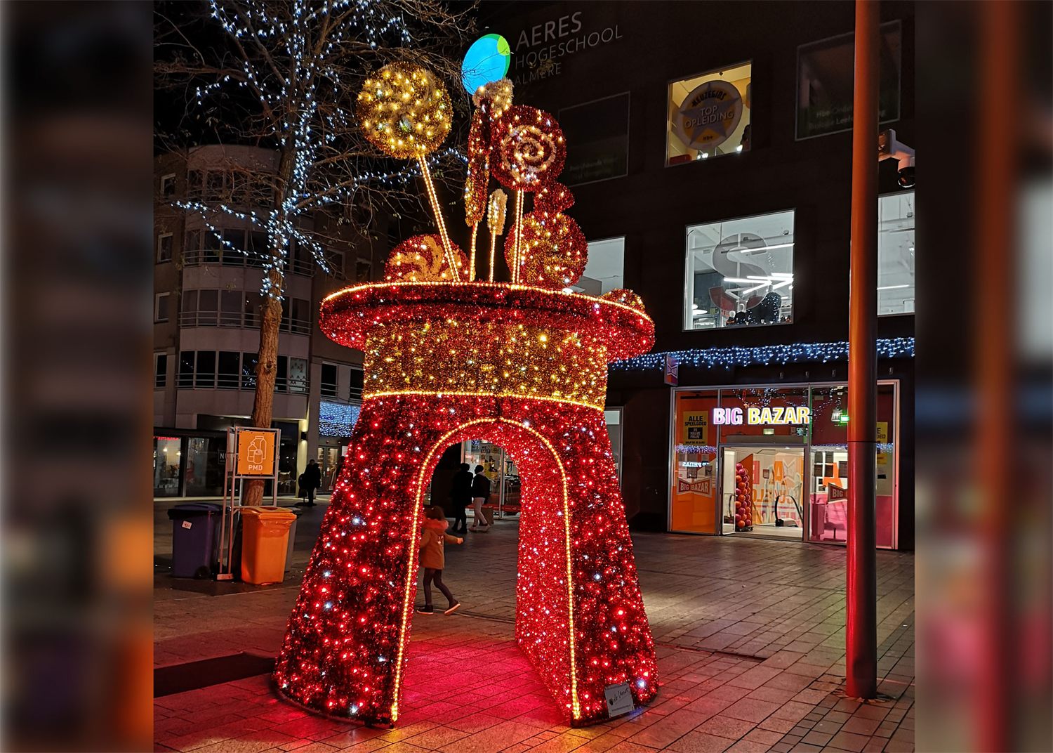 Rode verlichte reuzenhoed met lollies en ballonnen in een winkelcentrum