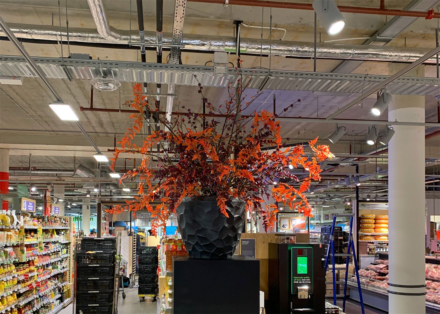 Groot herfstboeket met oranje takken in een zwarte vaas in een supermarkt