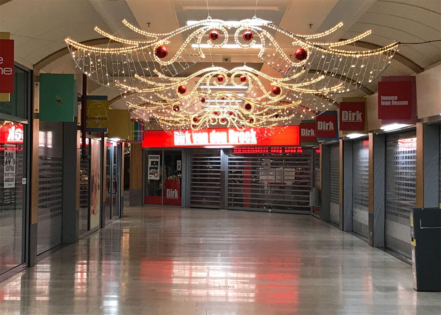 Passage van een winkelcentrum met warm witte lichtguirlandes en rode ballen aan het plafond
